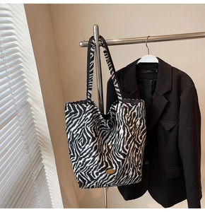 Detail of zebra stripe tote bag showing the large capacity and golden handmade metal logo