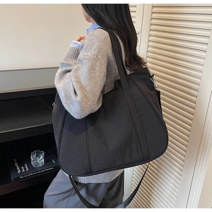 Detail van een grote zwarte nylon draagtas met matte textuur en verstelbare riem