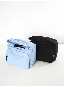 Detail of minimalist nylon crossbody bags in blue and black with zipper and orange label