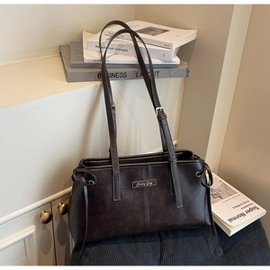 Close-up of dark brown matte leather shoulder bag with Sunny Day metal plaque and drawstring