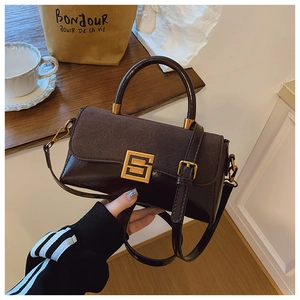 Detail der braunen Schultertasche mit Wildleder-Struktur und goldener S-Schnalle am Riemen