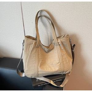 Detail van de kaki nylon draagtas met brede riem op een leren bank bij daglicht