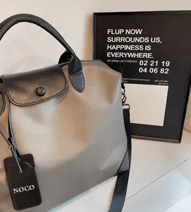 Dettaglio della borsa tote in nylon argento con manico in pelle nera e tracolla regolabile