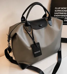 Dettaglio borsa da viaggio grigia in nylon impermeabile con manici in pelle nera