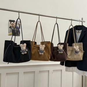 Macro view of suede tote bag texture with cute bear charm and thin shoulder strap