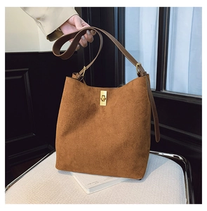 Detailed close-up of brown suede bucket bag with adjustable strap and golden metal clasp