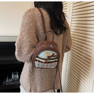 Detail view of mini PU leather backpack with patchwork bow and star patterns on brown fabric