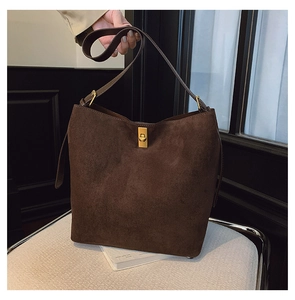 Detailed view of dark brown suede bucket bag with luxury gold-tone metal clasp