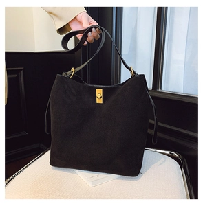 Detail of black suede tote bag with large capacity and elegant gold metal twist lock