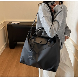 Dettaglio macro della borsa da viaggio in nylon nero con manici in pelle e tag NOCO