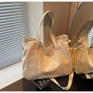 Detail van een grote crèmekleurige nylon shopper met verstelbare riem en metalen haken