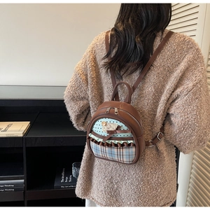 Detail showing bow and lace design on brown leather mini backpack worn by model