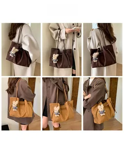 Detail view of large faux suede tote bags in brown and tan with drawstring and bear charm