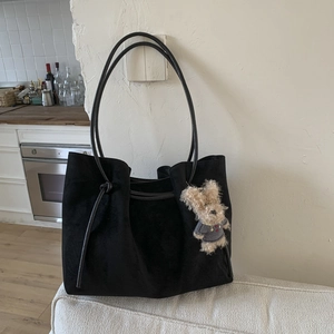 Detail of vintage matte suede tote bag with slim straps and a plush bear pendant