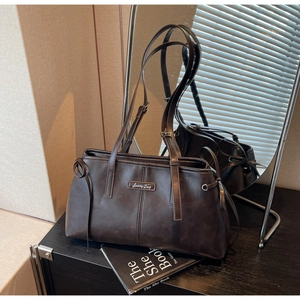 Detail of dark brown matte leather pillow bag with Sunny Day metal label and knot decor
