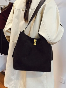 Large black suede tote bag with golden lock and wide shoulder strap on model
