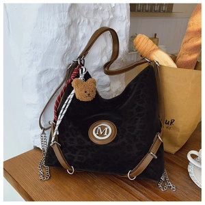 Detail of leopard print hobo bag with M logo, chain strap and bear plush charm accessory