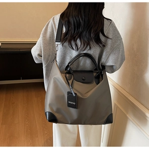 Dettaglio della borsa tote in nylon kaki con finiture in pelle nera e tracolla rimovibile