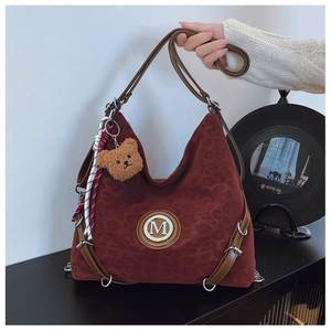 Close-up of leopard pattern tote bag with gold M logo and cute bear charm accessory