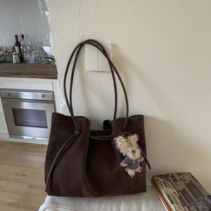 Detail view of large dark brown suede tote bag with a cute bear plush charm