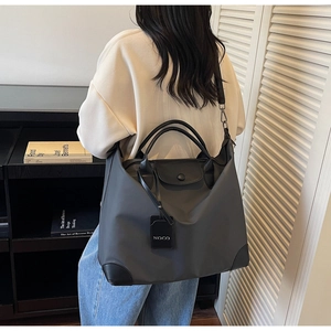 Borsa da viaggio in nylon grigio scuro con dettagli in pelle nera indossata da una modella