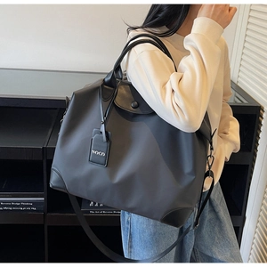 Dettaglio borsa da viaggio in nylon nero con manici in pelle e tracolla regolabile