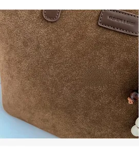 Macro view of brown suede tote bag featuring fashion label and beaded charm detail
