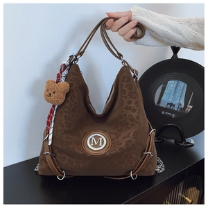 Close-up of leopard print tote bag with metallic logo, silk scarf and teddy bear charm