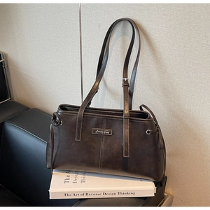 Detail of adjustable double shoulder straps on brown frosted leather pillow bag