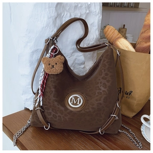 Detail of leopard print tote bag with metal M logo, chain strap and plush bear charm
