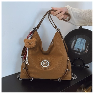 Detail of leopard print hobo bag featuring metal M logo and brown plush bear charm