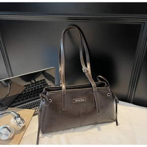 Close-up of vintage brown leather pillow bag with Sunny Day metal tag and adjustable strap