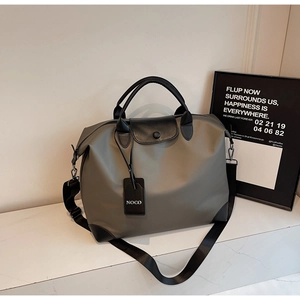 Dettaglio macro in nylon grigio con manico in pelle nera e targhetta NOCO della borsa