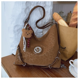 Close-up of leopard print tote bag featuring a metallic M logo and plush bear charm
