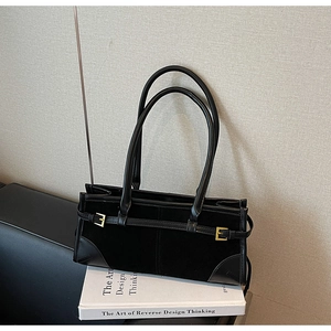Close-up of black suede and leather baguette bag with gold metal buckle details