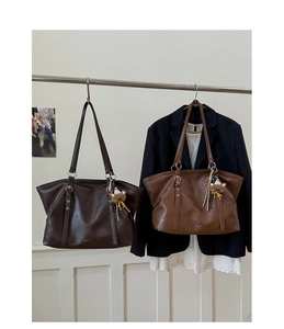 Brown leather tote bags hanging on a rack with a decorative bear charm detail