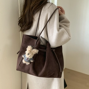 Detail of dark brown faux suede tote bag with a cute plush bear charm on the side