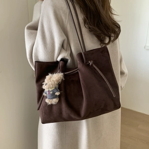 Detailed macro view of deep brown suede tote bag with a cute curly teddy bear charm