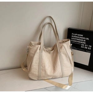 Detailopname van de crème nylon tote bag met verstelbare riem op marmeren blad