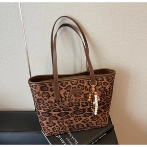 Detailed view of leopard print tote bag with brown handles and beaded tassel charm