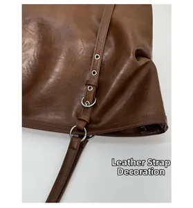 Detail of dark brown leather tote bag side with silver eyelets and belt strap decoration