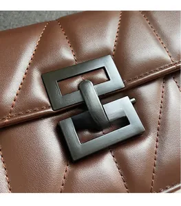Detail of chocolate brown quilted leather bag featuring a matte black square metal lock