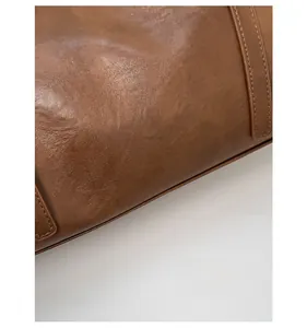 Close-up of deep brown textured leather tote bag featuring a silver brand logo detail