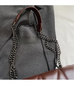 Close-up of deep brown quilted leather shoulder bag with vintage metal chain strap