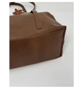 Detail showing the reinforced base and fine stitching of a brown vintage tote bag