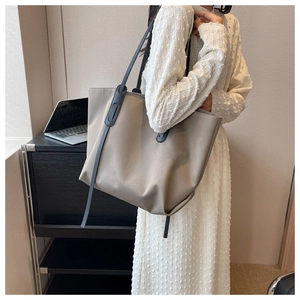 Détail d'un grand sac cabas beige en Oxford avec lanières en cuir noir porté par un mannequin
