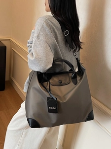 Grande borsa da viaggio in nylon taupe con manici in pelle nera portata a spalla