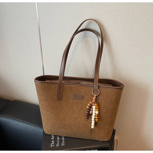 Detail of vintage brown suede tote bag featuring multi-color wooden bead tassel accent