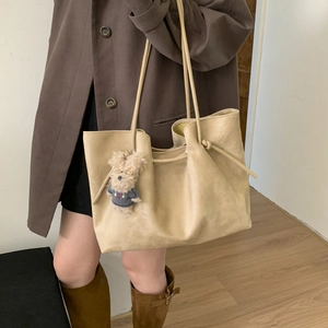 Detail of a large cream tote bag with a cute plush dog pendant and smooth matte finish