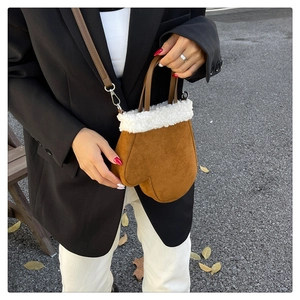 Detailed close-up of brown suede glove-shaped handbag with white faux fur trim and strap